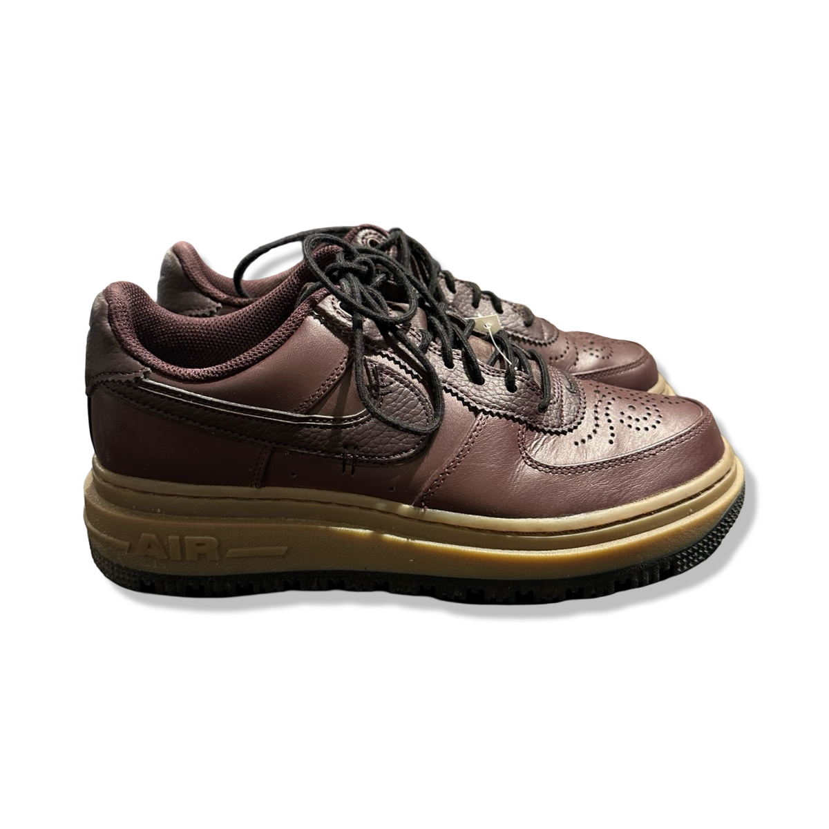 Ett par bruna Nike Air Force 1 Luxe sneakers i läder för dam, fotograferade från sidan mot en vit bakgrund.