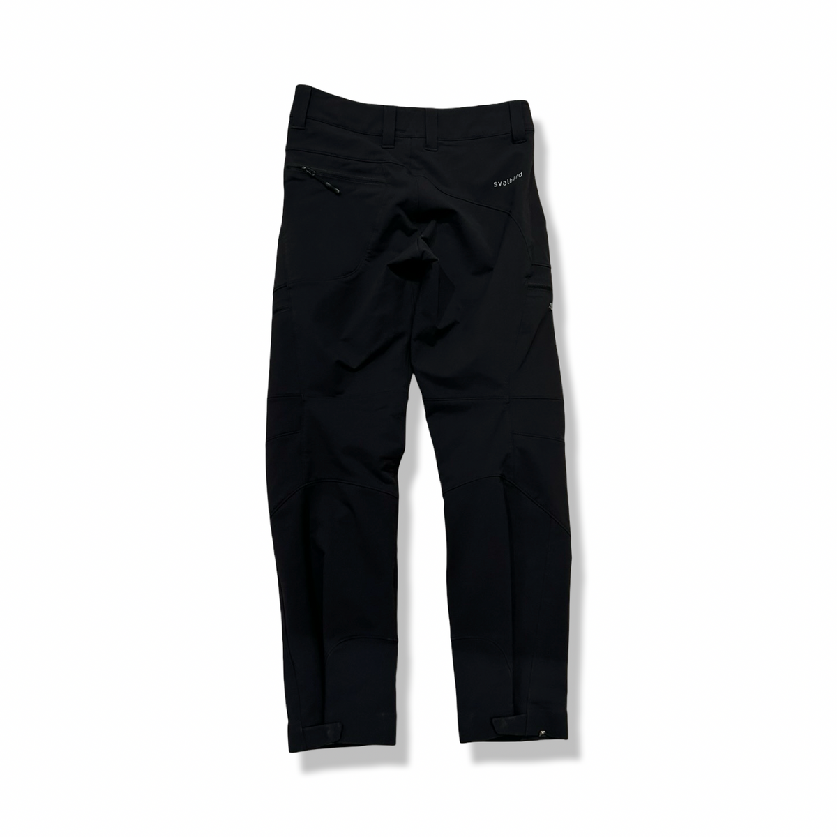 Baksidan av ett par svarta Norröna svalbard flex pants för dam, fotograferade mot en vit bakgrund.