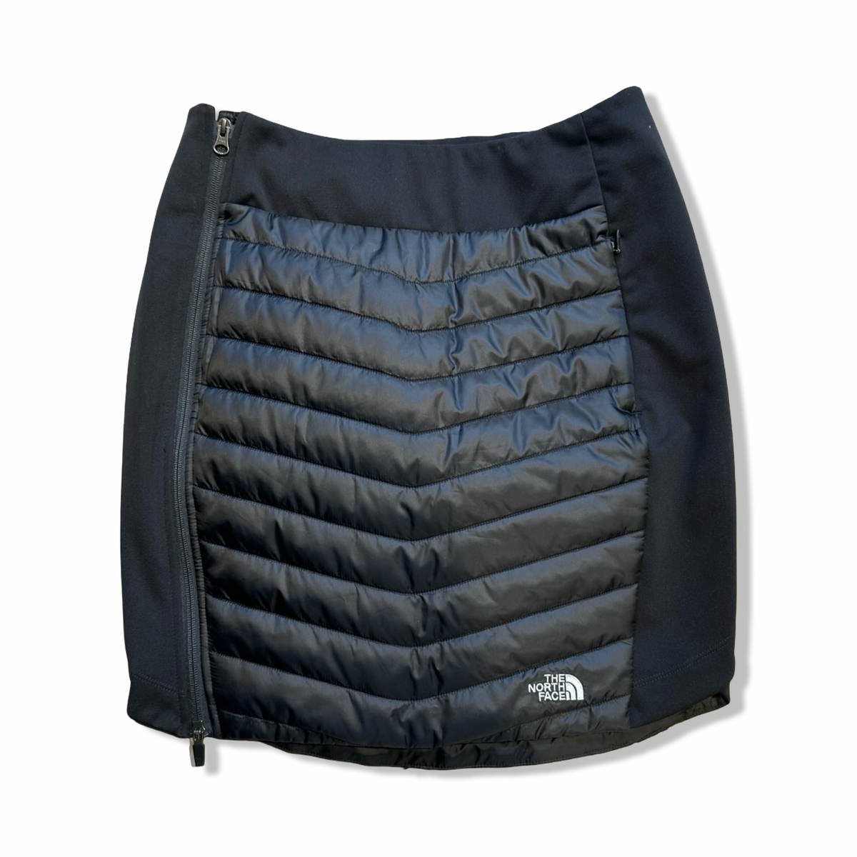 Svart Primaloftkjol från The North Face för dam med dragkedja i sidan, fotograferad framifrån mot en vit bakgrund.