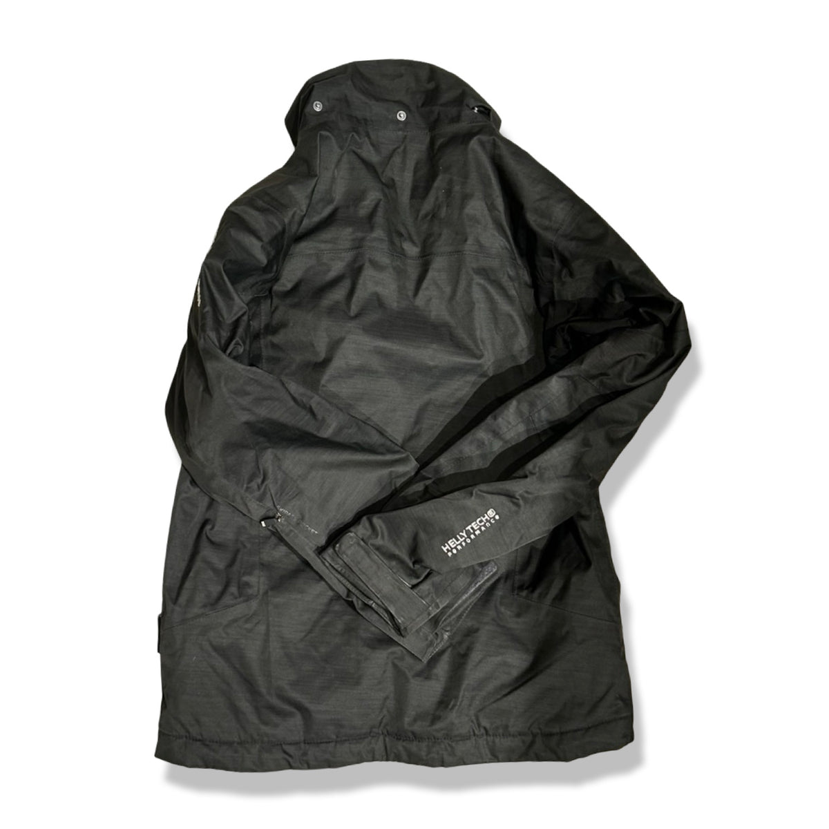 Baksidan av en svart skidjacka från Helly Hansen för barn i storlek 152, fotograferad mot vit bakgrund.