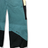 Närbild på en blå/vit Peak Performance skalbyxa med svarta detaljer och Gore-Tex Pro-logotyp, mot en vit bakgrund.