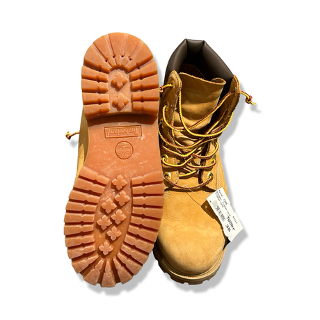 Ett par bruna Timberland-kängor för dam i storlek 38, visade med en sula vänd uppåt mot vit bakgrund.