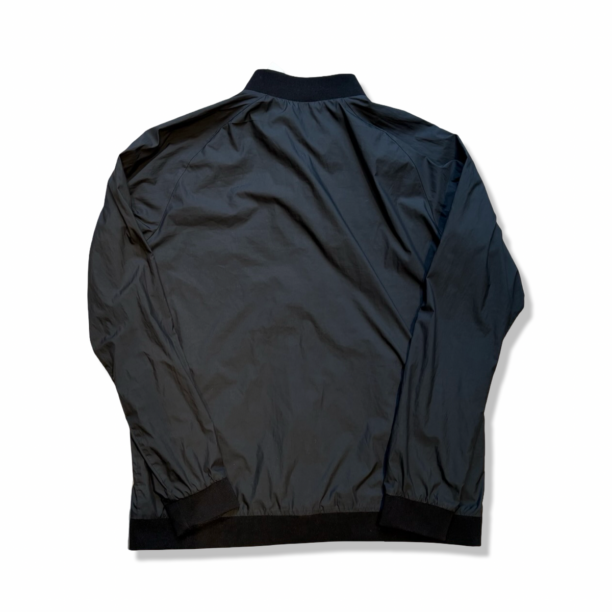 Baksidan av en svart träningsjacka från Peak Performance modell G Octon Jacket, fotograferad mot en vit bakgrund.