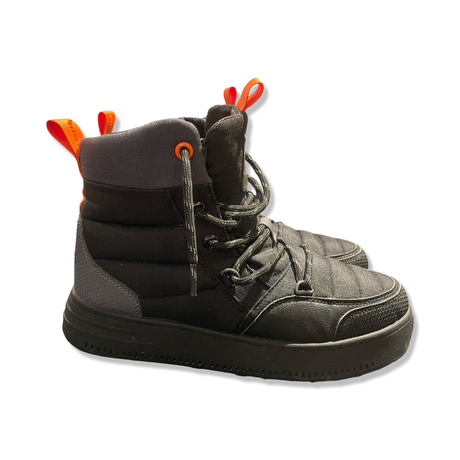 Ett par svarta Swims snowboot-kängor med orangea detaljer, fotograferade från sidan mot en vit bakgrund.