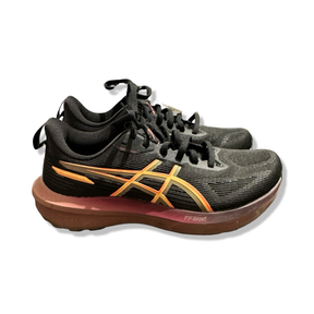 Svarta löparskor Asics GT-1000 14 för dam med orangea detaljer, fotograferade från sidan mot en vit bakgrund.