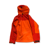 Orange och röd Arc'teryx Alpha AR Gore-Tex Pro skaljacka för dam, baksida fotograferad mot vit bakgrund.