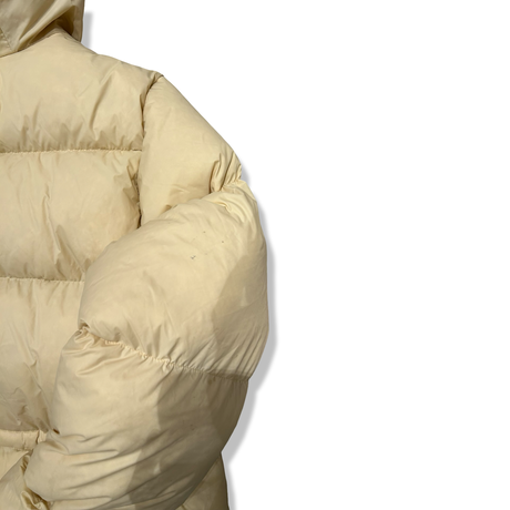 Gula dunjackan Peak Performance W Down Hood parka för dam, visad i en detaljbild på ärmen mot vit bakgrund.