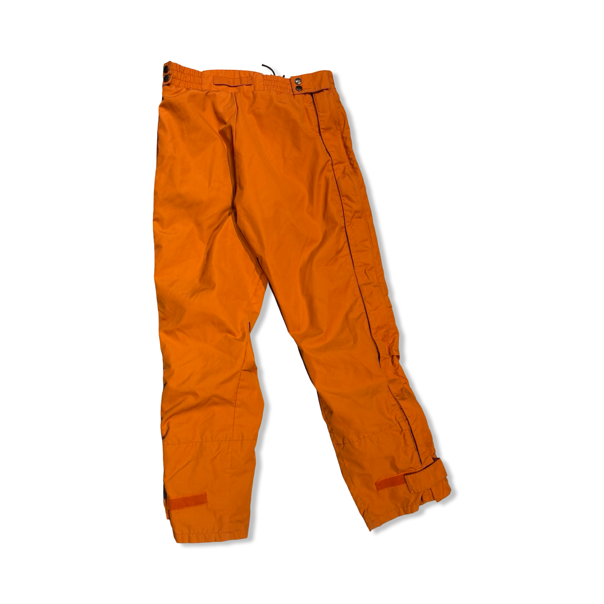 Baksidan av ett par orange funktionsbyxor från Fjällräven för dam, fotograferade mot en vit bakgrund.