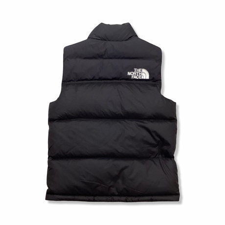 Baksidan av en svart väst från The North Face för barn, fotograferad mot en vit bakgrund.