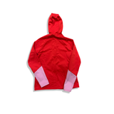 Baksidan av en röd och rosa fleecehoodie från Peak Performance för dam med huva, fotograferad mot en vit bakgrund.