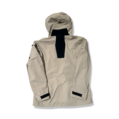 Baksidan av en beige Peak Performance W Alpine Gore-Tex skaljacka för dam, fotograferad mot en vit bakgrund.