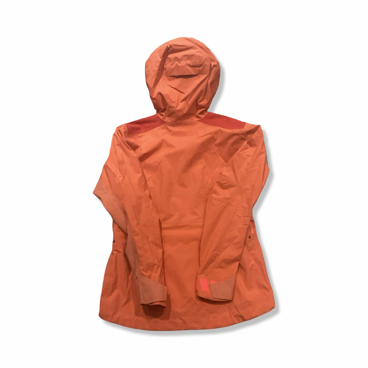 Baksidan av en orange Gore-Tex Pro skaljacka för dam med huva, fotograferad mot en vit bakgrund.