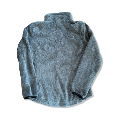 Grå fleecetröja för dam från The North Face i mjukt, lurvigt material, sedd bakifrån mot vit bakgrund.