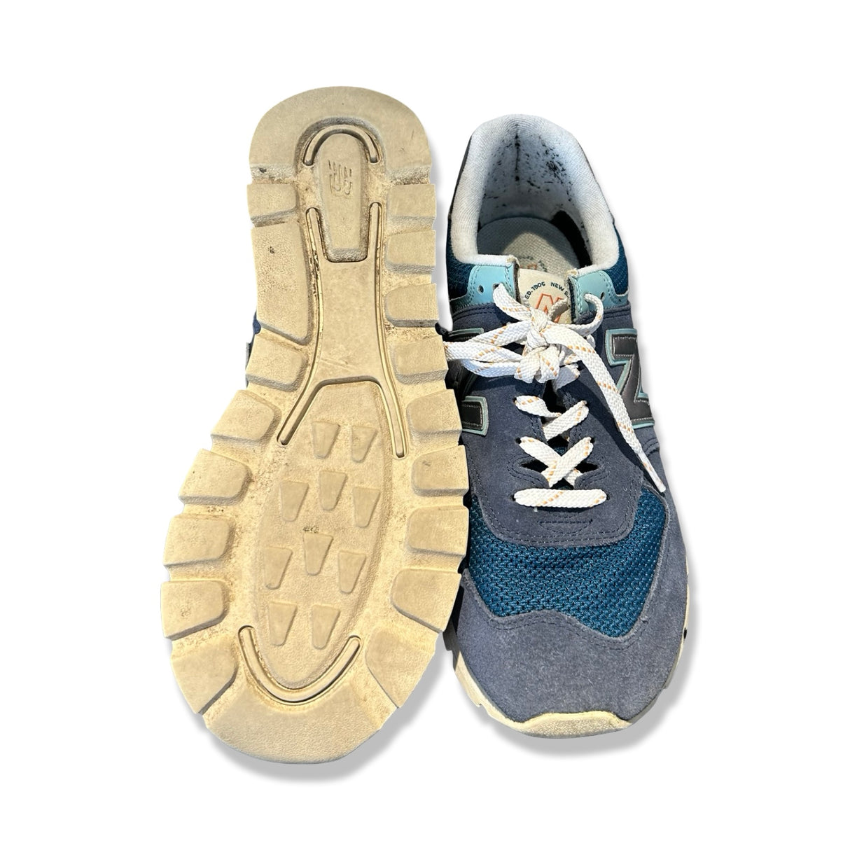 Blå New Balance sneakers för herr i mocka och mesh, fotograferade framifrån och med sulan uppåt.