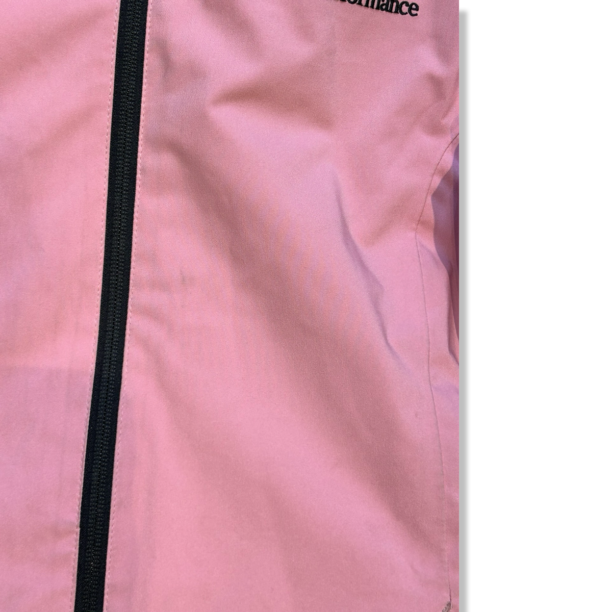 Närbild på en rosa skidjacka från Peak Performance för barn med svart dragkedja, som visar materialets skick.