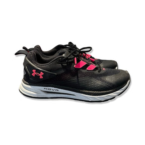 Svarta Under Armour HOVR löparskor för dam med rosa detaljer och vit sula, sedda från sidan mot en vit bakgrund.
