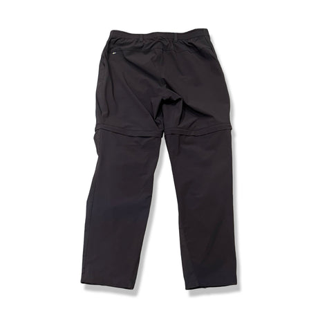Baksidan av ett par mörkblå Fjällräven Abisko Hybrid Trail Trousers för dam, fotograferade mot en vit bakgrund.