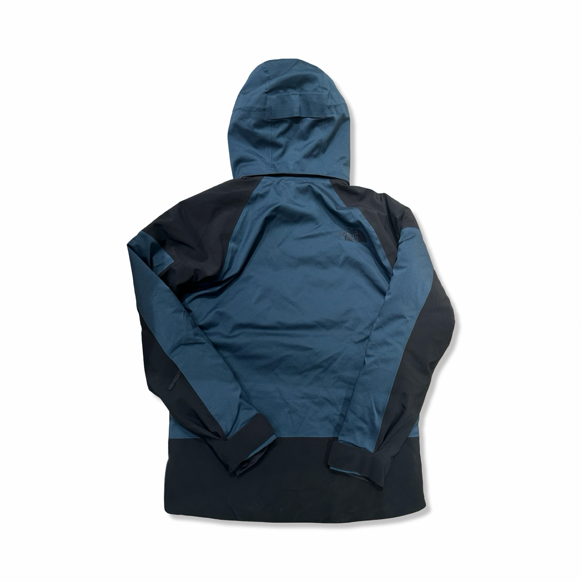 Baksidan av en blå och svart skidjacka från The North Face för herr med huva, fotograferad mot en vit bakgrund.